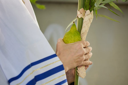 Succot. Jewish man in a Tallit praying while waving the Four Species, Lulav and Etrog