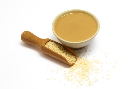 Sesame Seeds and Tahini. A bowl of creamy tahini next to a scoop of sesame seedsの写真素材