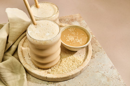 Sesame Tahini Latte Delight. Creamy sesame paste and iced tahini lattes on rustic travertine surface.の写真素材