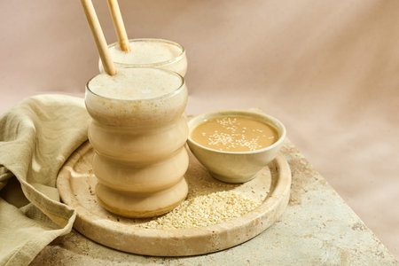 Sesame Tahini Latte Delight. Creamy sesame paste and iced tahini lattes on rustic travertine...