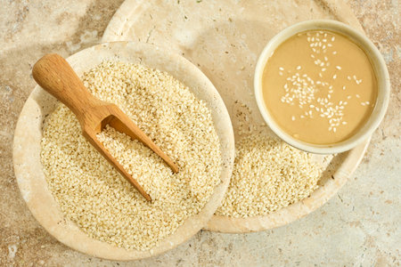 Sesame Tahini Bowl. A bowl of creamy tahini with sesame seeds on a rustic travertine surface.の写真素材