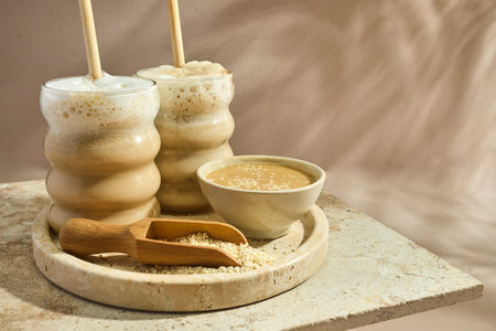 Sesame Tahini Latte Delight. Creamy sesame paste and iced tahini lattes on rustic travertine...