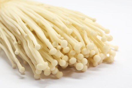 Enoki Mushrooms. Close-up of fresh enoki mushrooms against a white background.