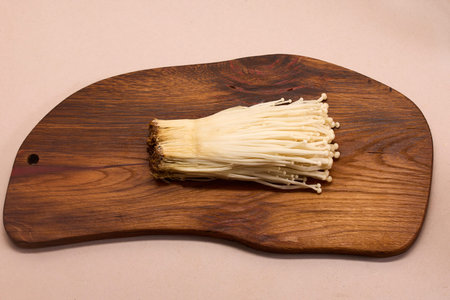 Enoki Mushrooms on Board. A bunch of enoki mushrooms are placed on a wooden cutting board
