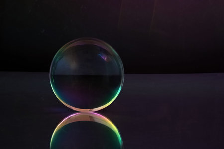 Ethereal Sphere. A glowing glass sphere with rainbow hues, reflecting on a sleek surface against a...
