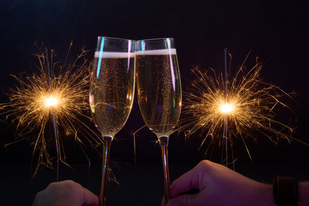 Celebration Toast. Two champagne glasses clinking with sparklers in a festive atmosphere. Happy New Yearの写真素材