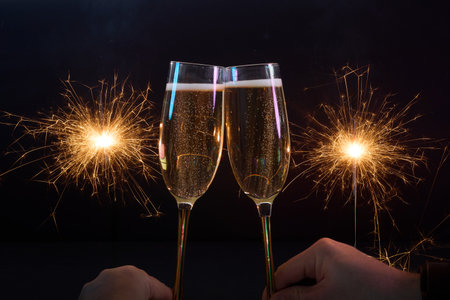 Celebration Toast. Two champagne glasses clinking with sparklers in a festive atmosphere. Happy New Yearの写真素材