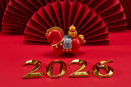 Year of the Horse 2026. Red horse figurine and gold 2026 on red fan backgroundの写真素材