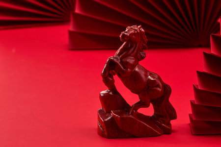 Red Horse Sculpture. Wooden horse figurine on a red background with folded paper decor.の写真素材