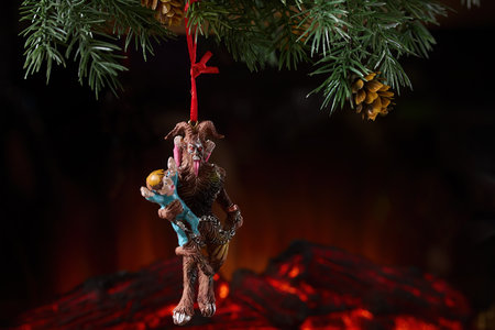 A Krampus ornament with child hanging from a Christmas treeの写真素材