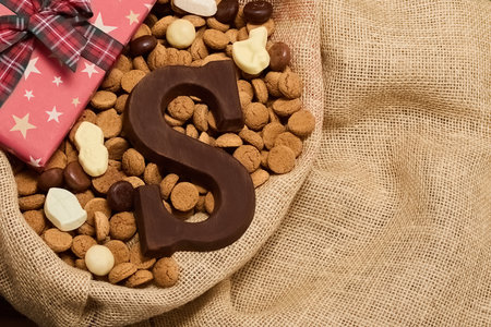 Festive Sinterklaas Display. A burlap basket with chocolate letters, Sinterklaas figures, and a starry gift boxの写真素材