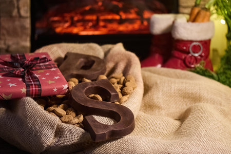 Cozy Holiday Fireplace Scene. Warm holiday ambiance with gifts, chocolate lettersの写真素材