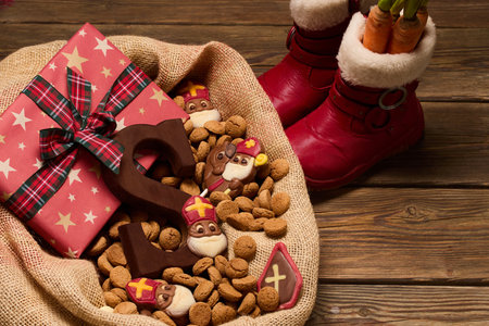 Festive Treats and Gifts. Sinterklaas chocolates and cookies in a burlap sack on a wooden table.の写真素材
