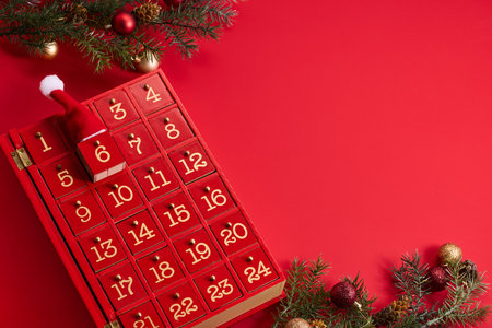 Festive Advent Calendar. Red advent calendar and Christmas decor on a vibrant red background.の写真素材