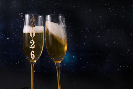 New Year Celebration. Two champagne glasses against a starry backdrop celebrating 2026.