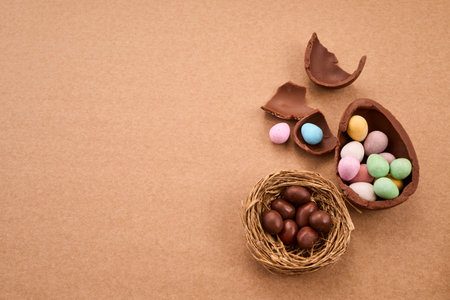 Chocolate easter eggs and candy scattered on brown background