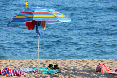 Umbrella at the sandy beach with wet clothes hanged to dryの写真素材