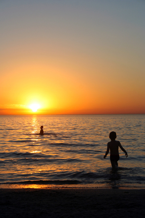 Two boys playing in the sea on sunsetの写真素材