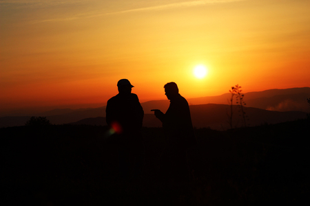 two men talking at sunsetの写真素材