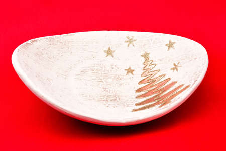 Christmas tree toys, holiday plate, brown stand, decorated with Golden Christmas tree and stars, on a red backgroundの写真素材