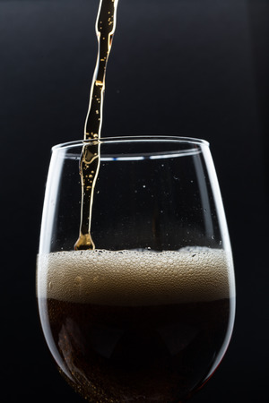 Glass of pouring fizzy drink with ice on a black backgroundの写真素材