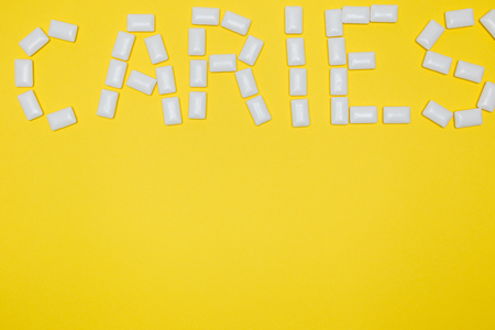 Gum in the form of caries lettering on a yellow backgroundの写真素材