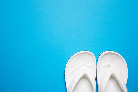 Flip flops on a blue isolated background. White female flip flops.の写真素材
