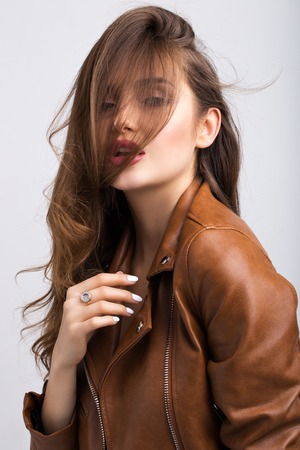 Portrait of a beautiful girl on a white background in a brown leather jacket.の写真素材