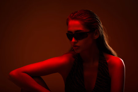 Portrait of a girl in sunglasses with a red light on a red background. Close-up. Isolated background.の写真素材