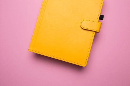 Diary of yellow color on a pink background isolated close-up.