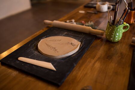 A master class in modeling a clay jug. Table with clay and a tool for creativity.の写真素材