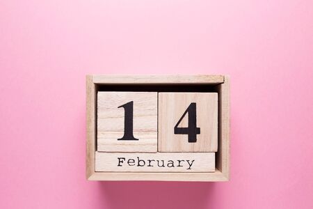 Wooden calendar with the inscription February 14 on a pink isolated background.の写真素材