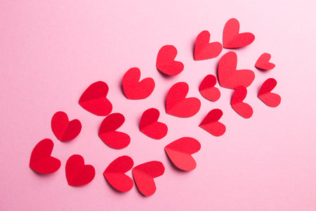 A lot of small hearts of red color against on a pink background. Happy Valentines Day.
