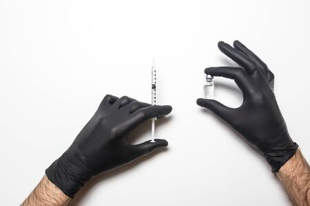 Male hand in a medical glove with a vaccine on a white background.の写真素材