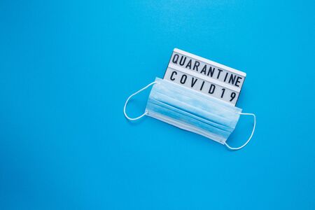 Inscription COVID-19 on blue background. Cube with the inscription. The inscription quarantine. The inscription quarantine. Blue medical mask.の写真素材