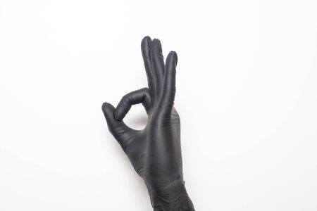 Medical glove in black on a white background. Hand showing okay sign.の写真素材