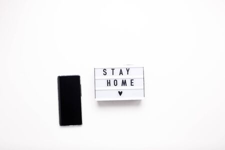 Stay home lettering on box and smartphone on a white isolated background.の写真素材