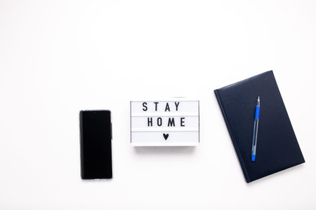 Stay home, boxing inscription. Remote online work at home. Headphones tablet and diary on a pink background.の写真素材