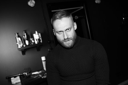 Portrait of a brutal man in a barbershop. Black and white photo of a bearded man.