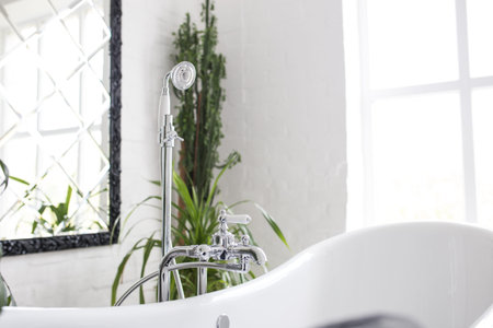 Faucet with shower in the bathroom close-up. Bright white room with greens.の写真素材