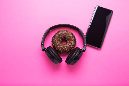 Donut and headphones on a pink background. Concept of business lunch and rest after work.の写真素材