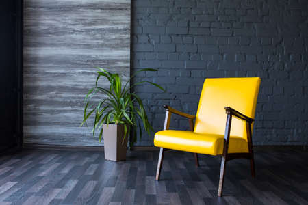 Stylish retro yellow chair in the gray room. Brick gray wall. Room.の写真素材