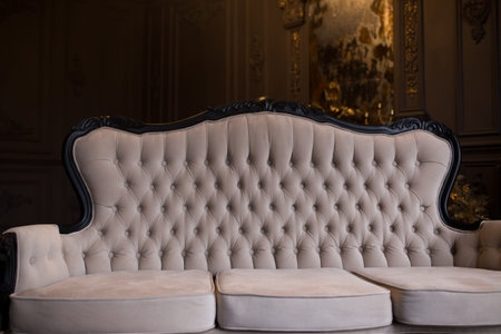 Ancient beige sofa in a dark room with a vintage mirror.