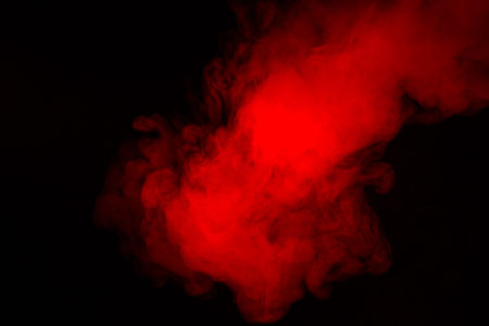 Colorful smoke close-up on a black background. Red cloud of smoke.
