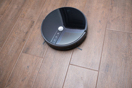 Robot vacuum cleaner on a brown laminate close-up.