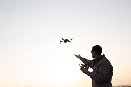 A man launches a drone into the sky. Drone operator with setting sun.の写真素材