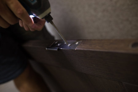 Drilling a hole in the furniture to install a lock on the door close-up.