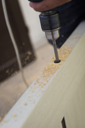 Drilling a hole in the furniture to install a lock on the door close-up.の写真素材