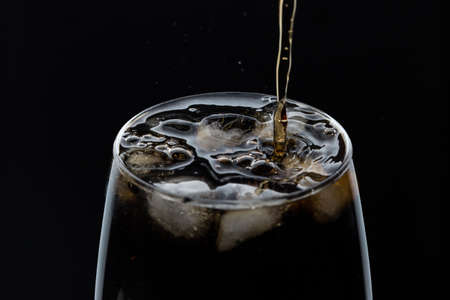 A glass of cola beverage with a salt. On a black background.の写真素材