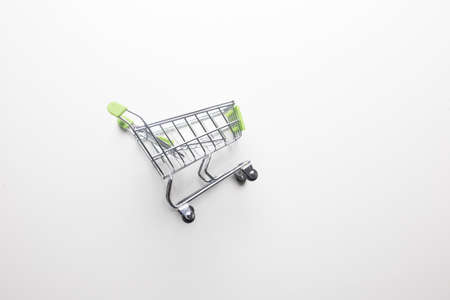 Grocery cart with light green handles on a white isolated background close-up.の写真素材